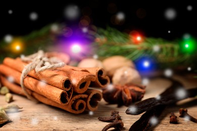 Different spices and fir tree branches on wooden table, closeup. Cinnamon, cloves, anise, cardamom, vanilla, nutmegs