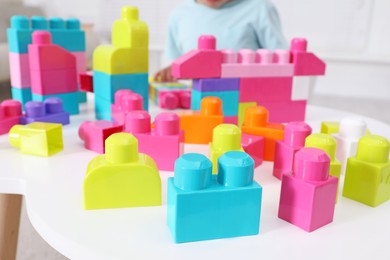 Little child playing with colorful building blocks at table indoors, closeup