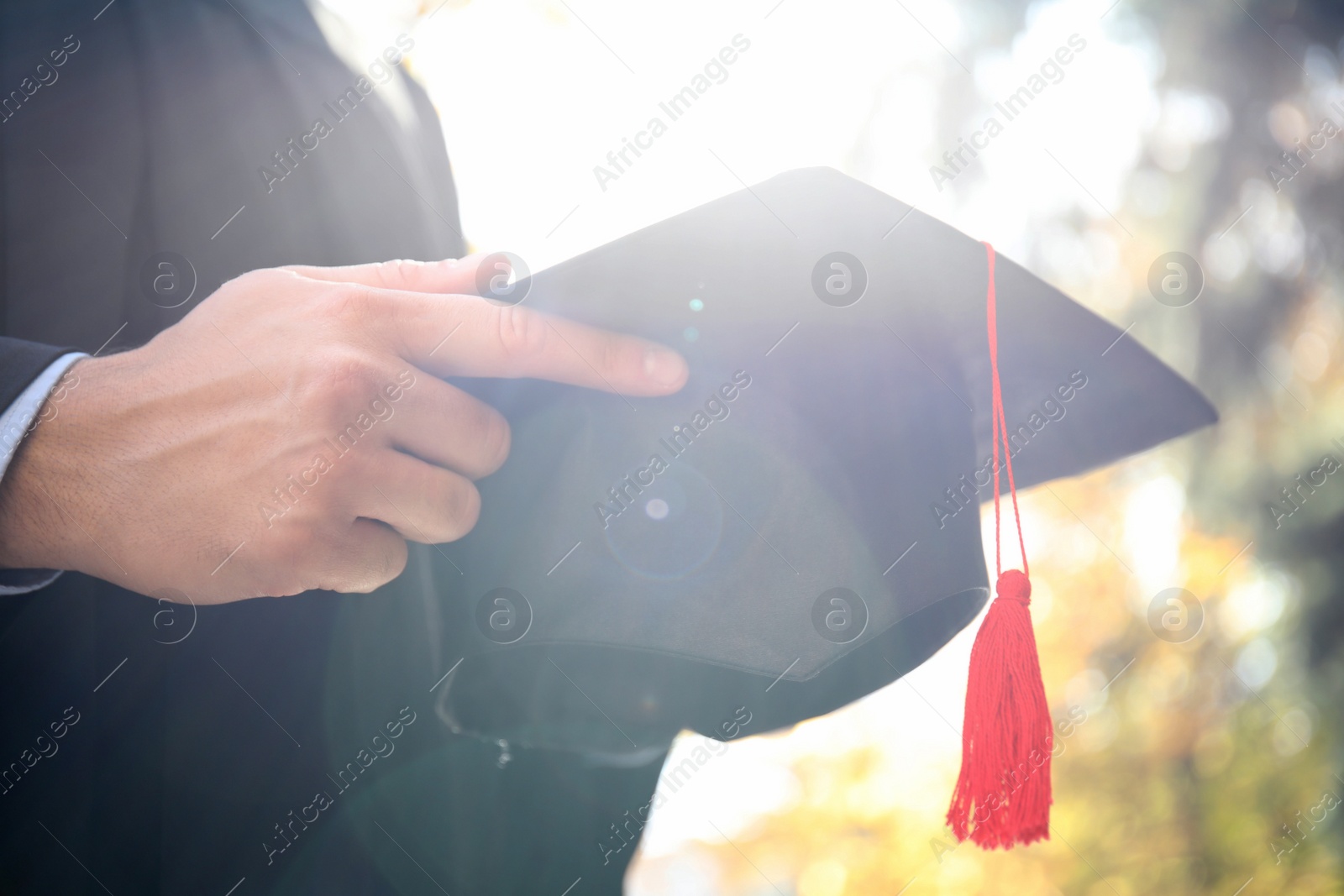 Photo of Student with graduation hat outdoors on sunny day, closeup