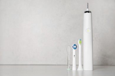 Electric toothbrush and replacement brush heads on light background, space for text