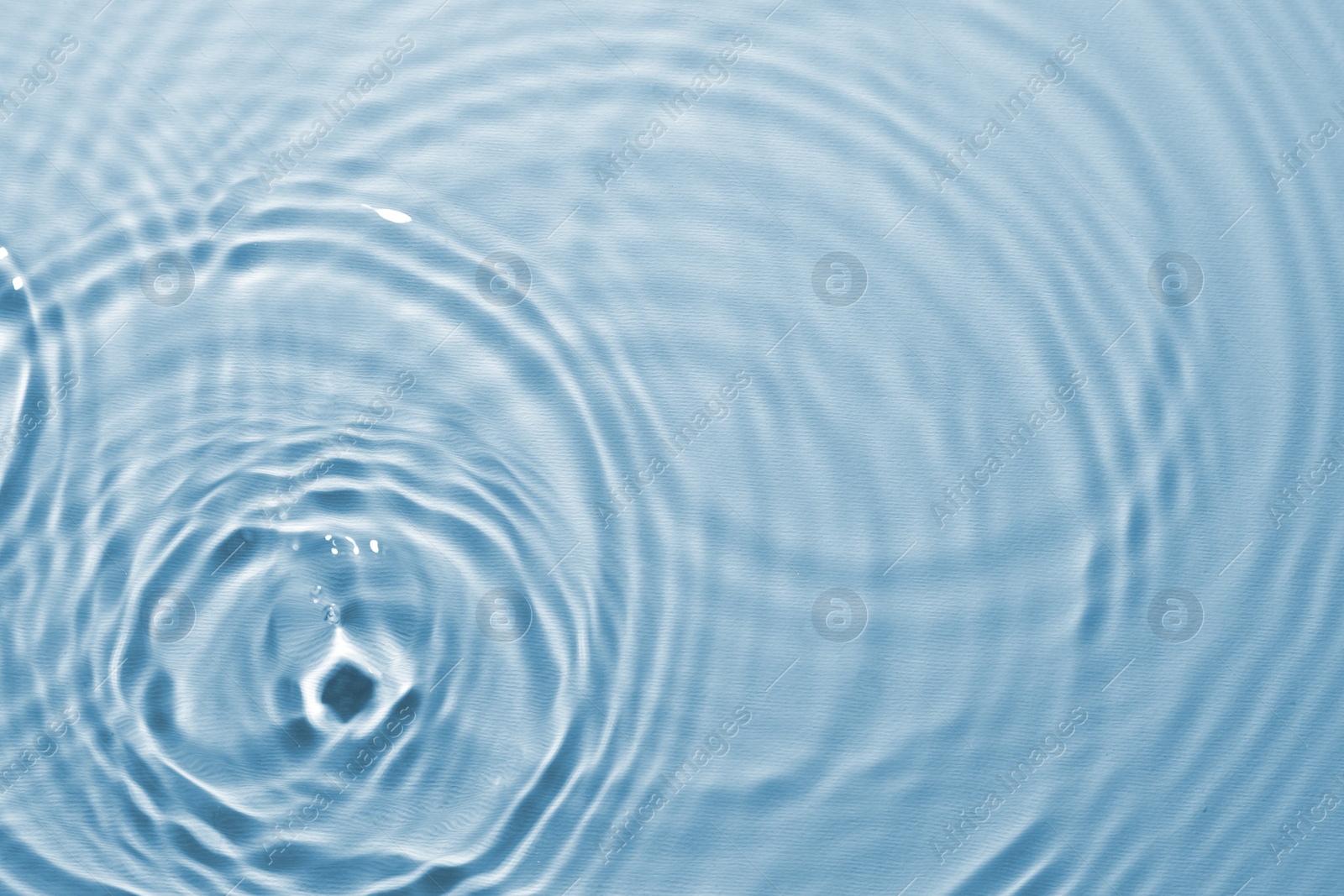 Image of Rippled surface of clear water on light blue background, top view