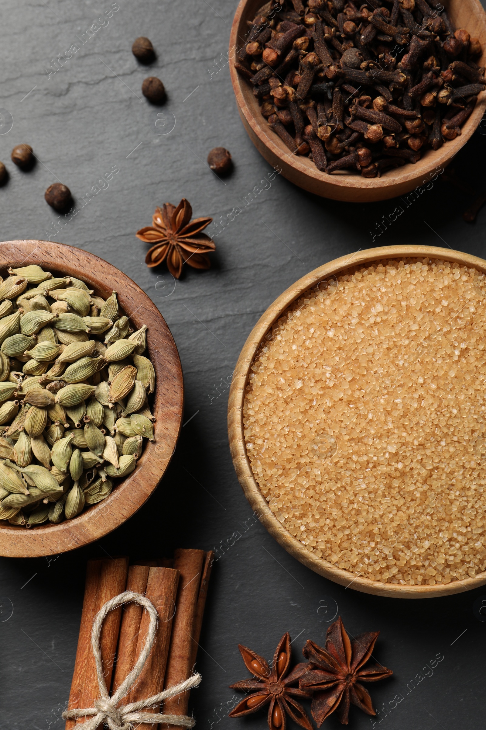 Photo of Different spices in bowls on dark gray textured table, flat lay