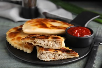 Photo of Delicious fried chebureki with ketchup on blue wooden table