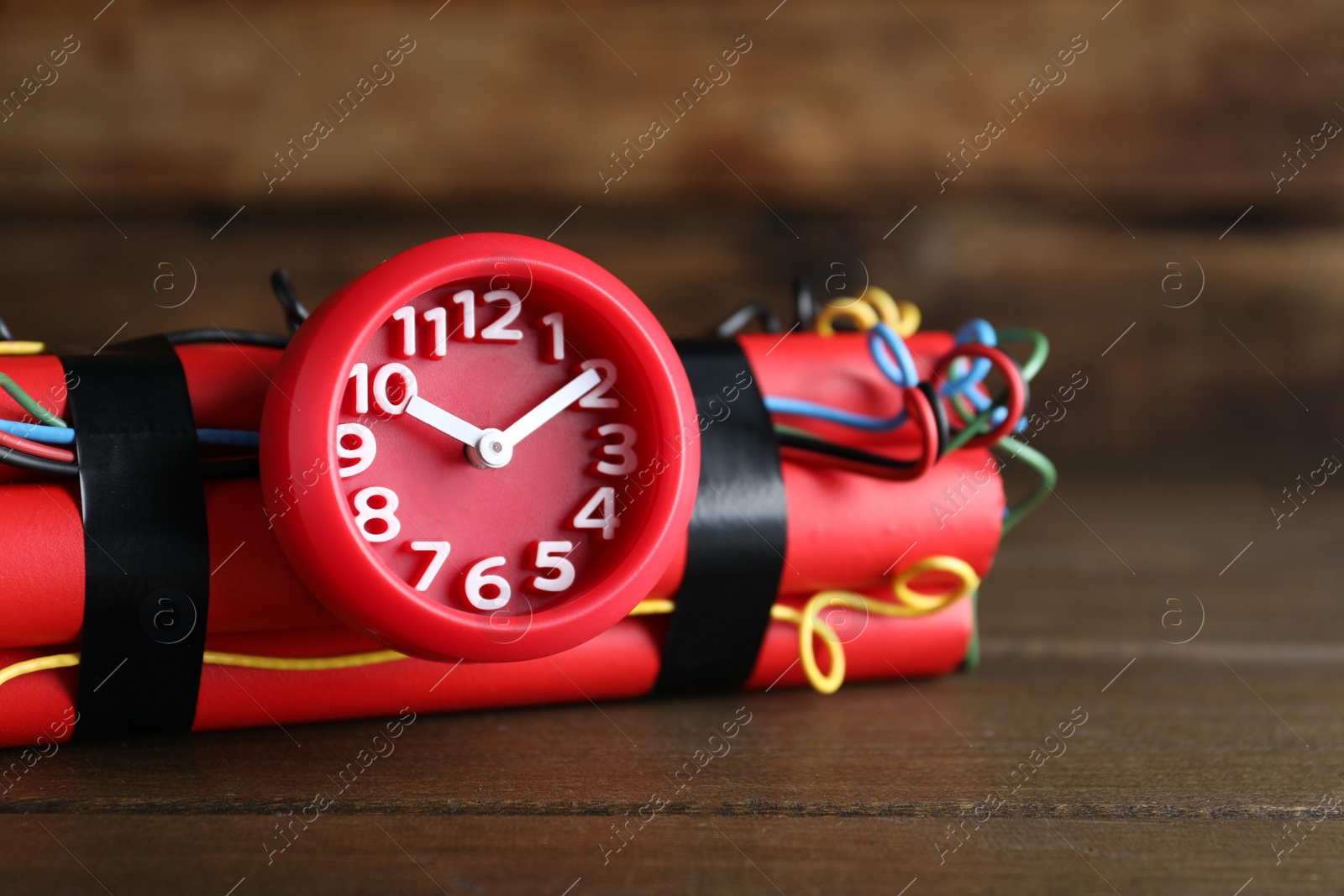 Photo of Dynamite time bomb on wooden table, closeup