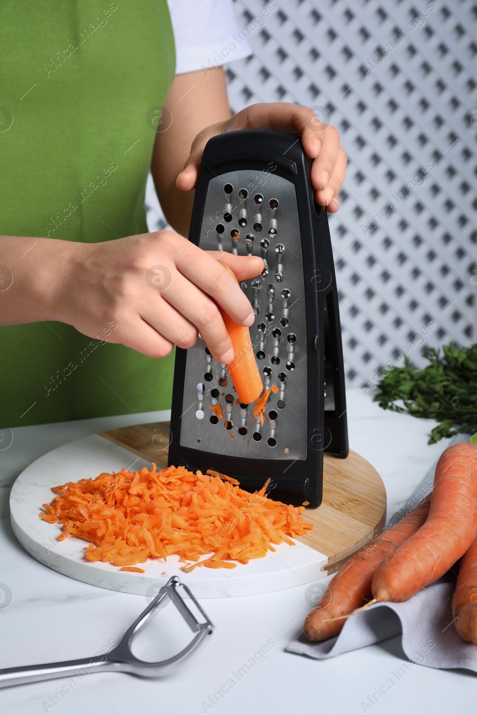 Photo of Woman grating fresh carrot at table indoors, closeup