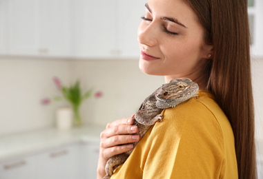 Woman holding bearded lizard in kitchen. Exotic pet