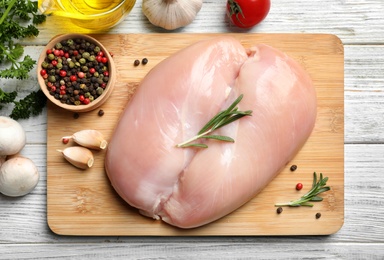 Flat lay composition with raw chicken breasts and ingredients on wooden background