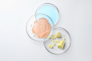 Photo of Many Petri dishes and cosmetic products on white background, top view