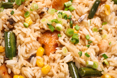 Photo of Delicious rice pilaf with chicken and vegetables as background, closeup