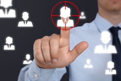 Image of Executive search (headhunting). Man touching human icon in target on digital screen against dark background, closeup