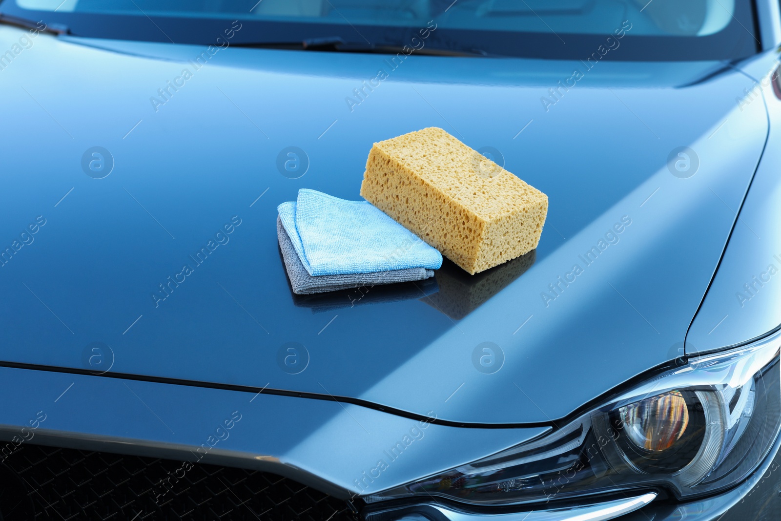 Photo of Sponge and rags on car hood. Cleaning products