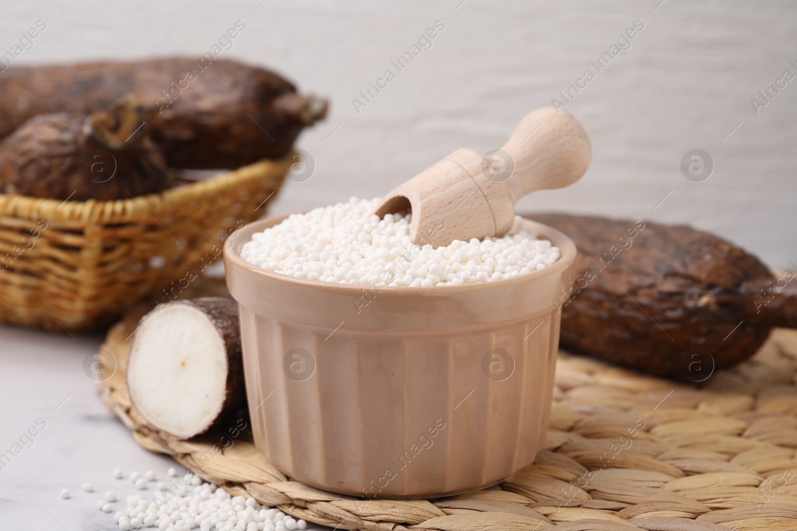 Photo of Tapioca pearls in bowl and cassava roots on wicker mat