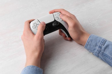 Photo of Man using wireless game controller at white table, closeup