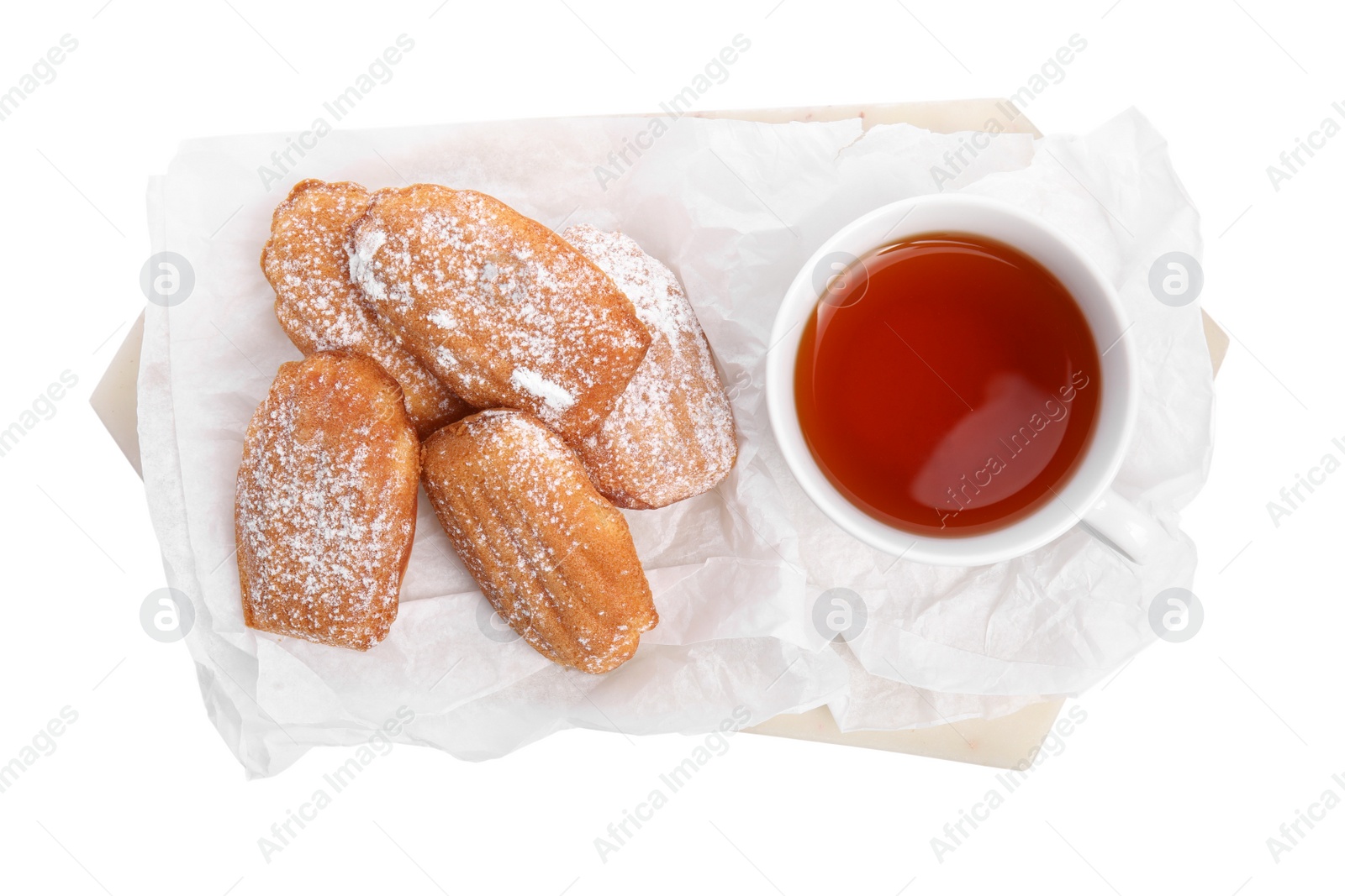 Photo of Delicious madeleine cakes with powdered sugar and tea on white background, top view