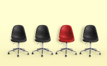Image of Vacant position. Red office chair among black ones on beige background