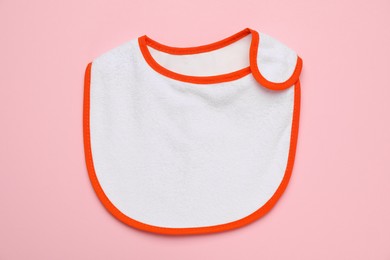 Photo of New baby bib on pink background, top view. First food