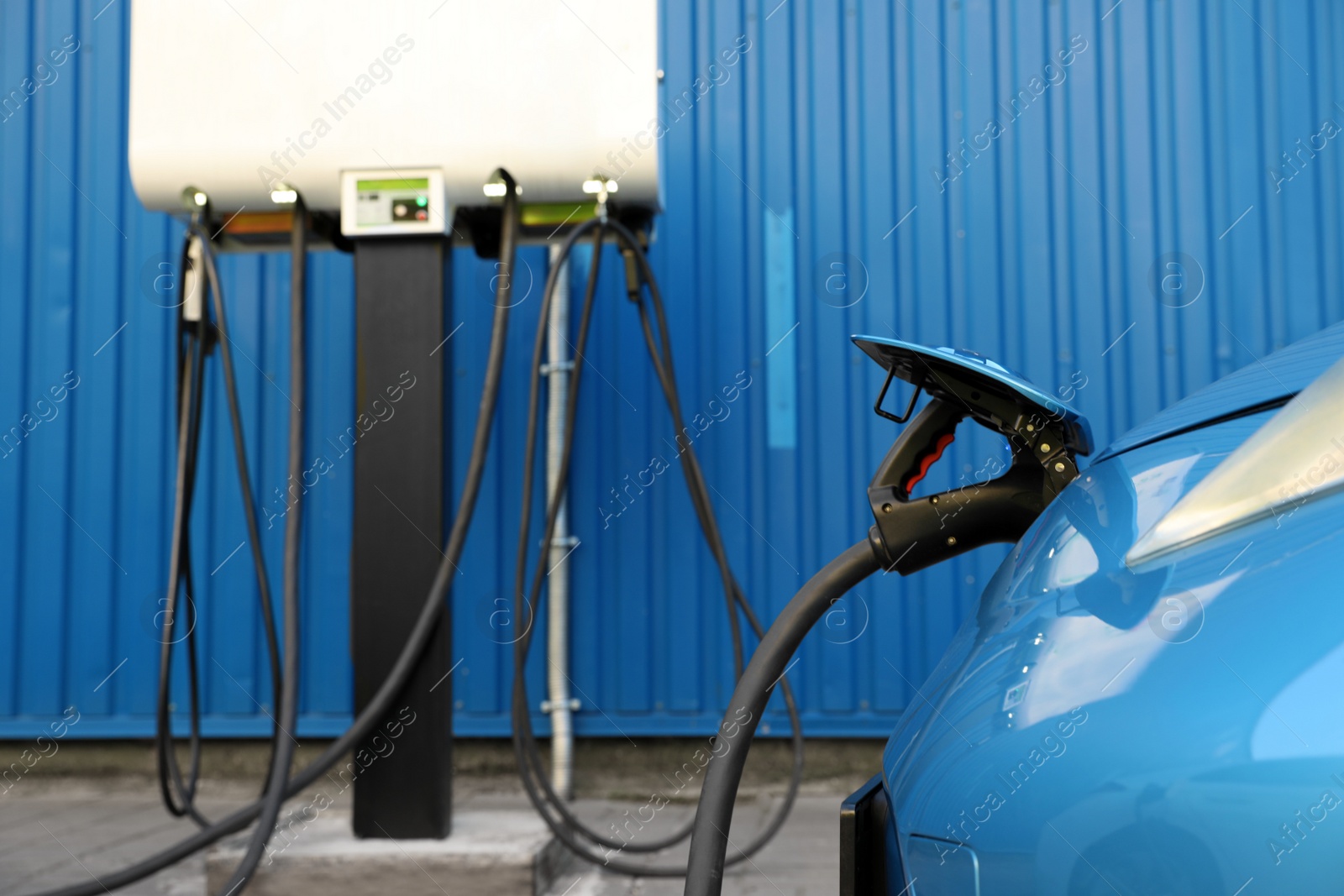 Photo of Charging modern electric car from station outdoors