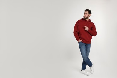 Photo of Happy man pointing at something on white background. Space for text