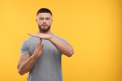 Photo of Man showing time out gesture on orange background, space for text