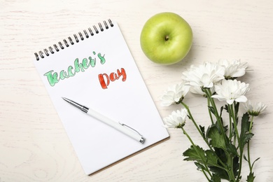 Flat lay composition with words TEACHER'S DAY, flowers and apple on white wooden table