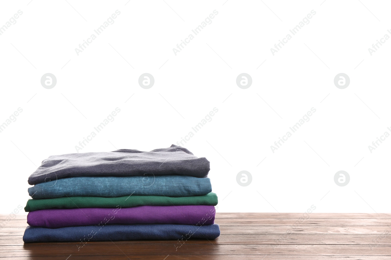 Photo of Pile of ironed clothes on table against white background. Space for text