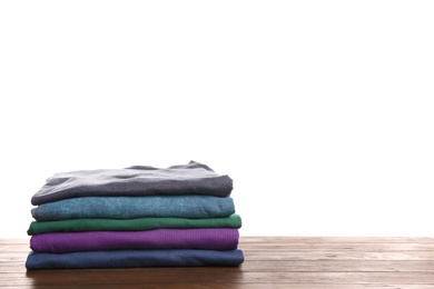 Photo of Pile of ironed clothes on table against white background. Space for text