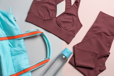 Photo of Gym bag, yoga sportswear and bottle of water on color background, flat lay