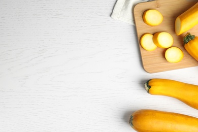 Photo of Flat lay composition with fresh ripe yellow zucchinis on white wooden table, space for text