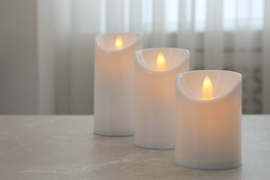 Photo of Glowing decorative LED candles on grey table. Space for text
