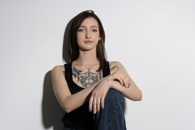 Portrait of beautiful tattooed woman on light background