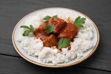 Photo of Delicious goulash with rice on grey wooden table, closeup
