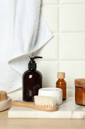 Different bath accessories and personal care products on wooden table near white tiled wall