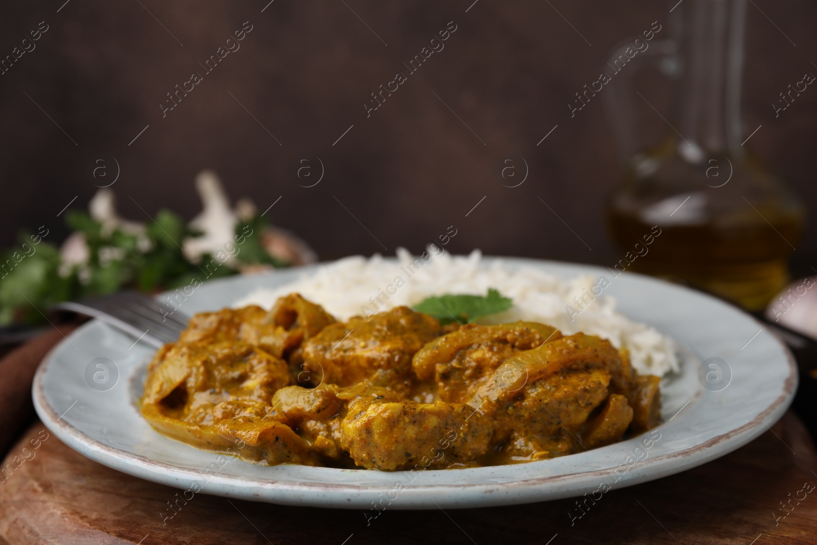 Photo of Delicious chicken curry with rice on wooden table, closeup