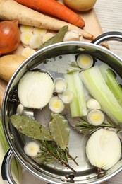 Pot and different ingredients for cooking tasty bouillon on white wooden table, flat lay