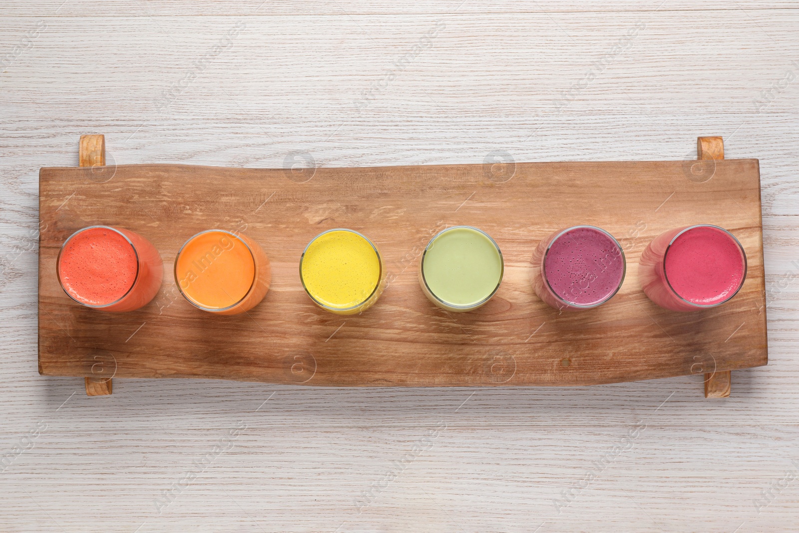 Photo of Board with many different tasty smoothies on white wooden table, top view