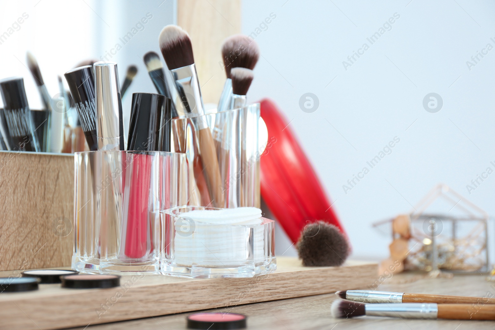 Photo of Organizer with cosmetic products for makeup on table near mirror