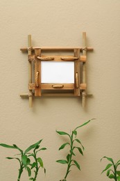 Photo of Green stems near beige wall with bamboo frame