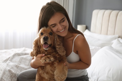 Photo of Young woman and her English Cocker Spaniel on bed indoors. Pet friendly hotel