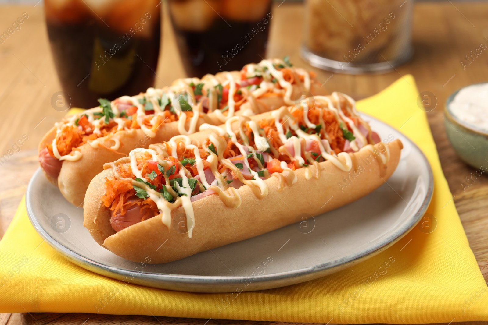 Photo of Delicious hot dogs with bacon, carrot and parsley on table, closeup