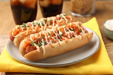 Delicious hot dogs with bacon, carrot and parsley on table, closeup