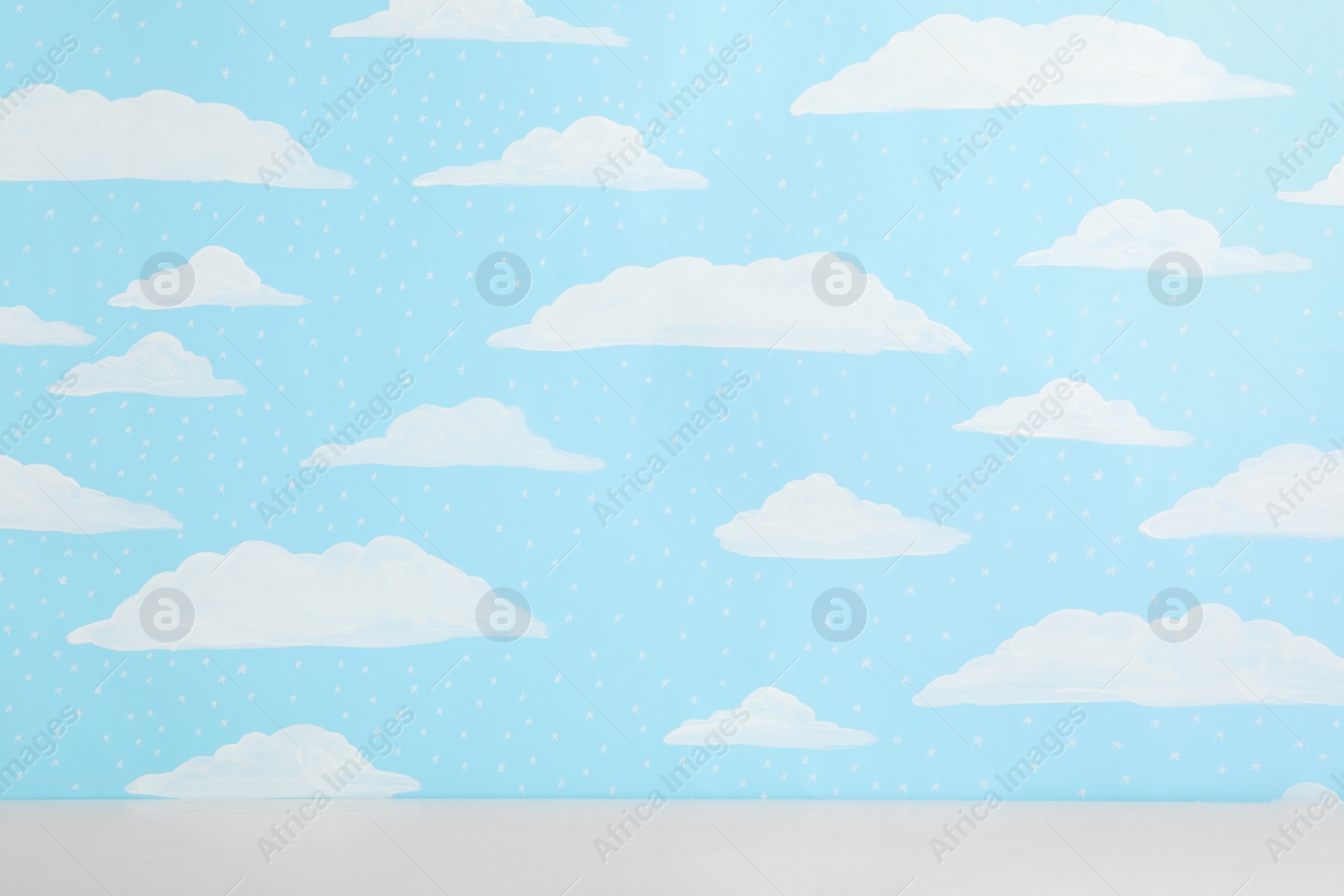 Photo of White table near wall with painted blue sky. Idea for baby room interior