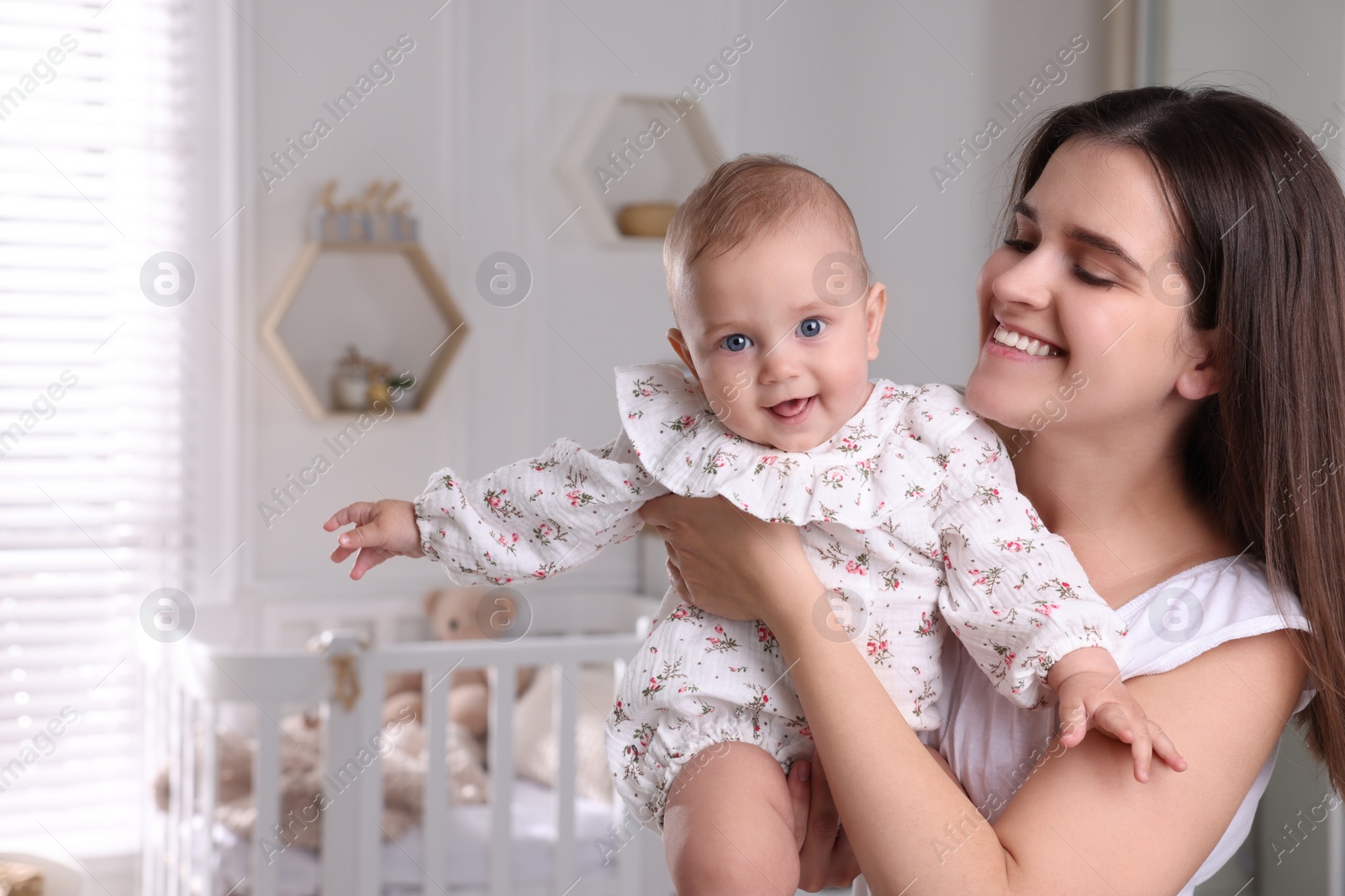 Photo of Happy young mother with her baby daughter in nursery