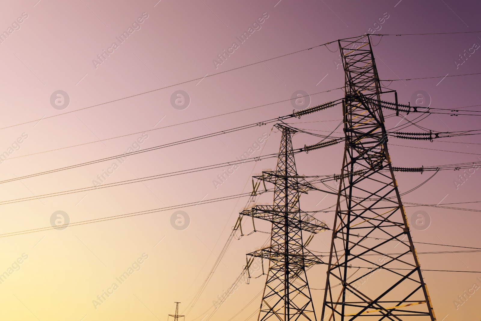 Photo of High voltage towers at sunset, low angle view