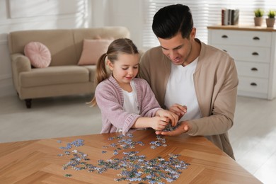 Man and his little daughter playing with puzzles at home