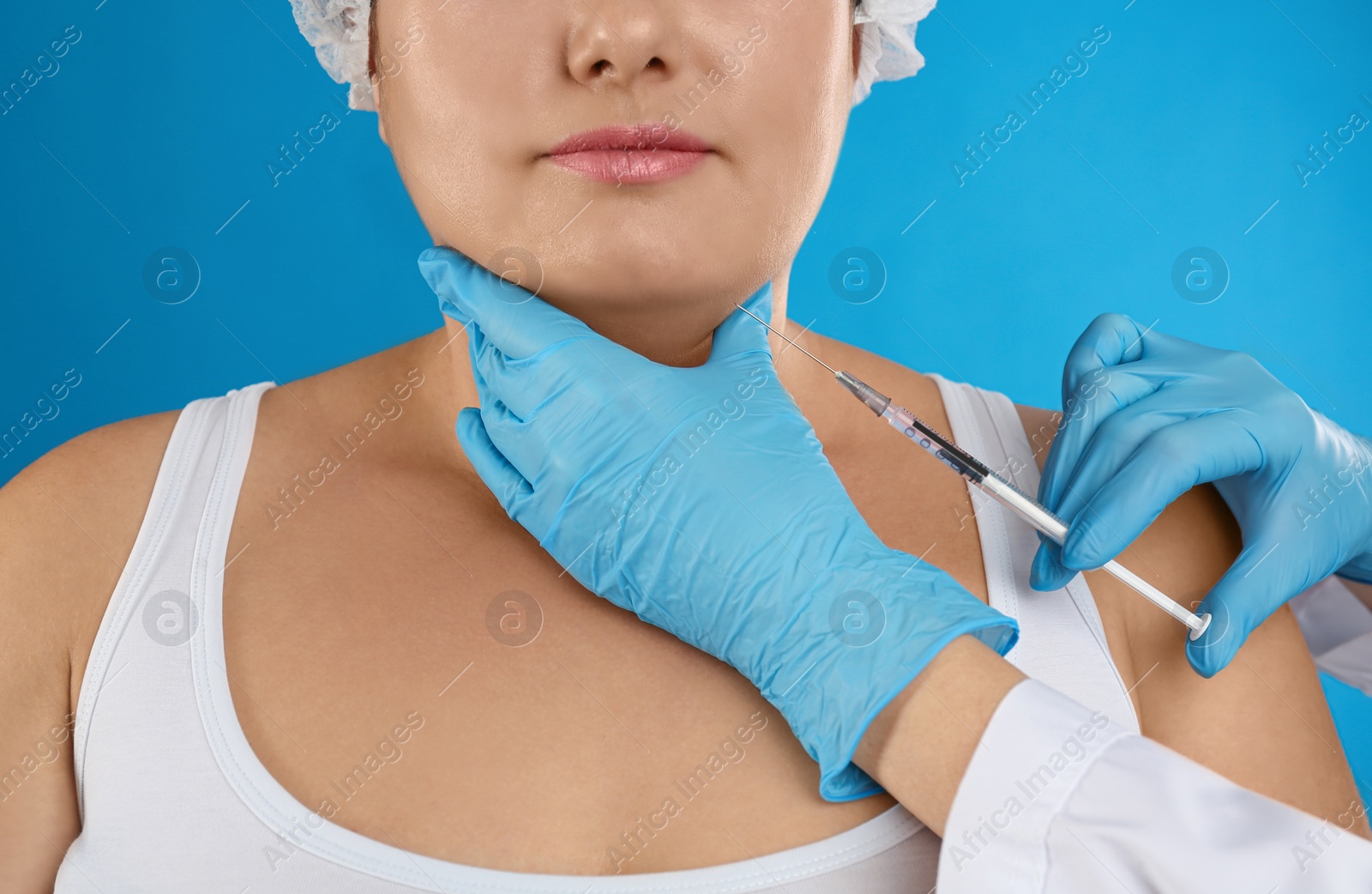 Photo of Woman with double chin getting injection on blue background, closeup. Cosmetic surgery