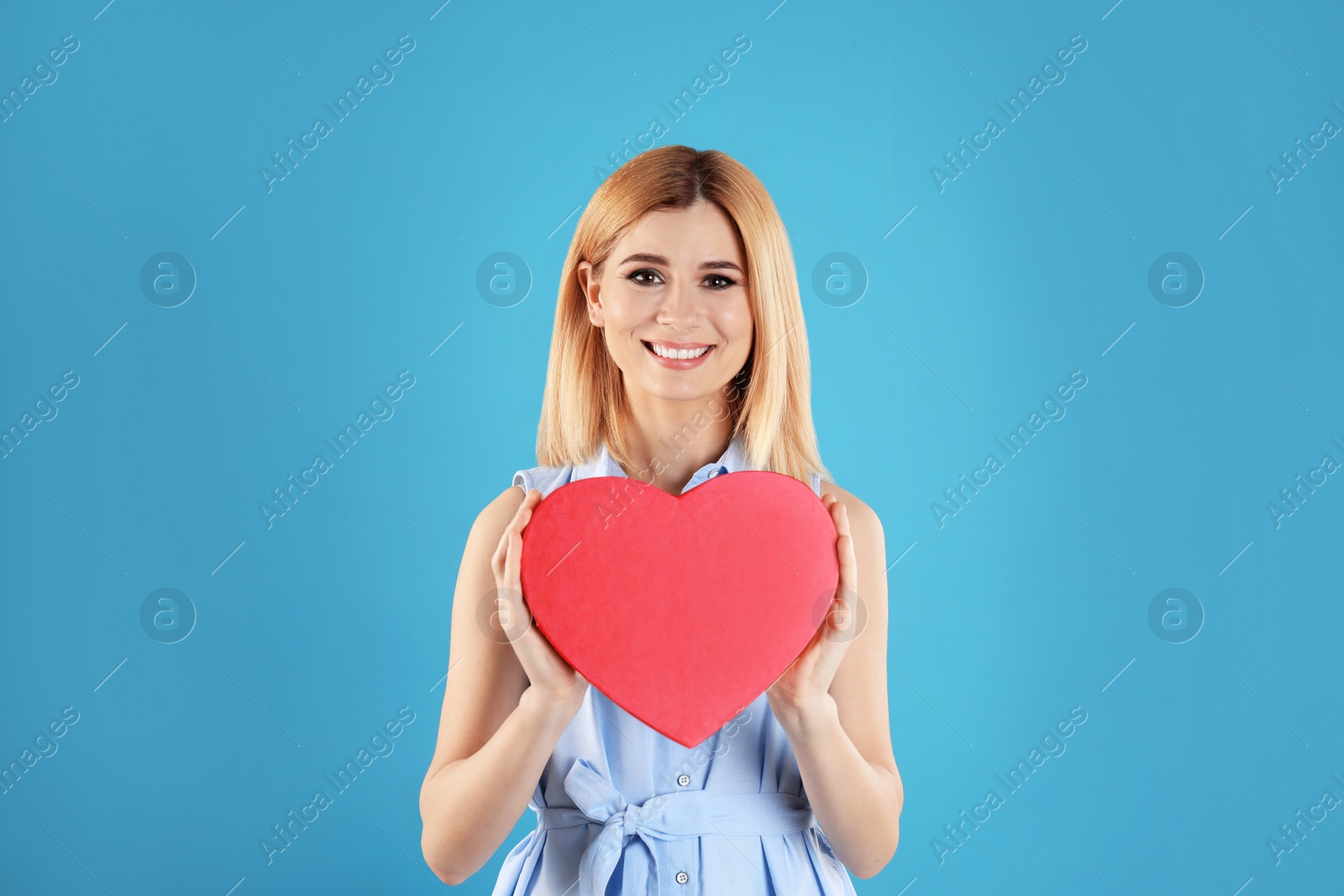 Photo of Beautiful woman with heart shaped box on color background