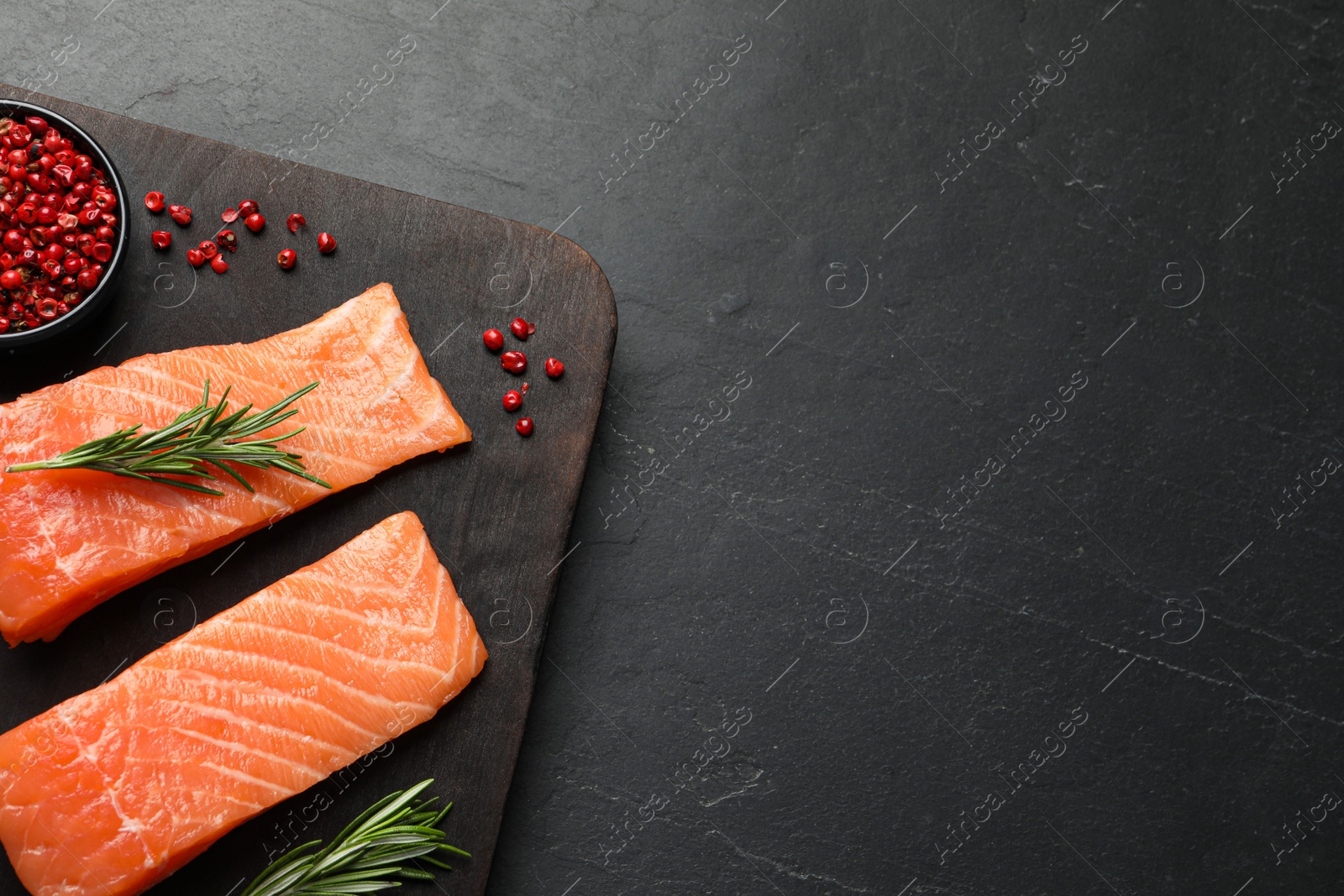 Photo of Fresh raw salmon and spices on black table, top view. Space for text