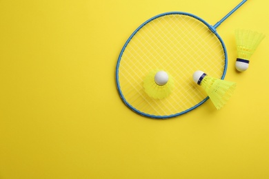 Photo of Badminton racket and shuttlecocks on yellow background, flat lay. Space for text
