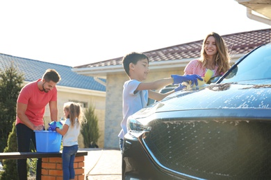 Happy family washing car at backyard on sunny day
