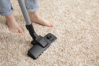 Photo of Woman cleaning carpet with vacuum cleaner, closeup. Space for text